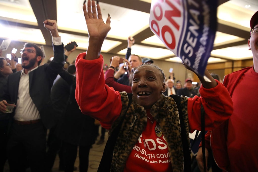 a woman in a red sweatshirt celebrates as election results come in a woman in a red sweatshirt celebrates as election results come in