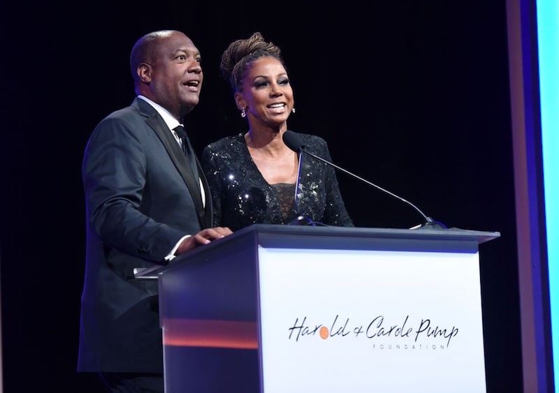 The couple speaks to an audience while standing at a podium. The couple speaks to an audience while standing at a podium.