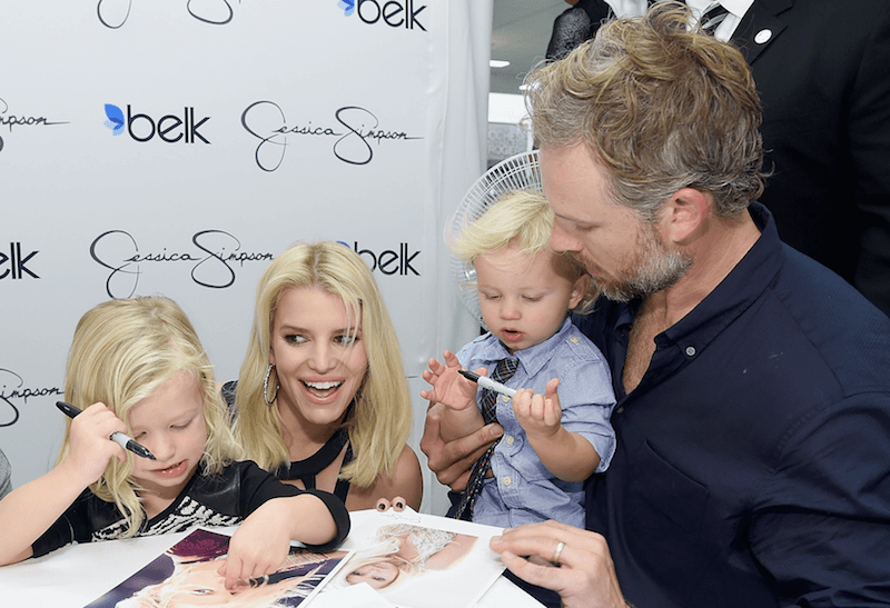 Jessica Simpson and Eric Johnson signing autographs with their children. 