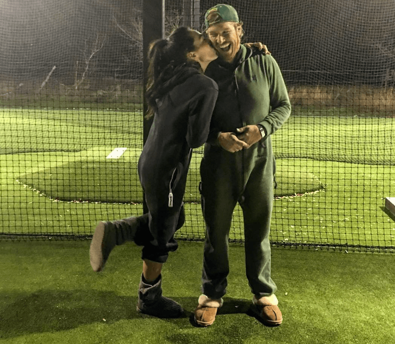 Joanna kisses Chip's cheek as they wear onesies on a field. Joanna kisses Chip's cheek as they wear onesies on a field.