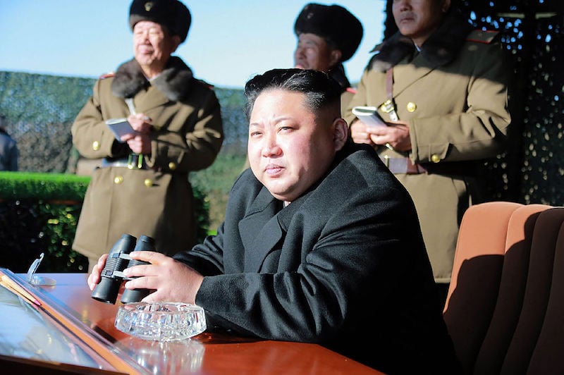 Kim Jong Un holding binoculars and sitting outside