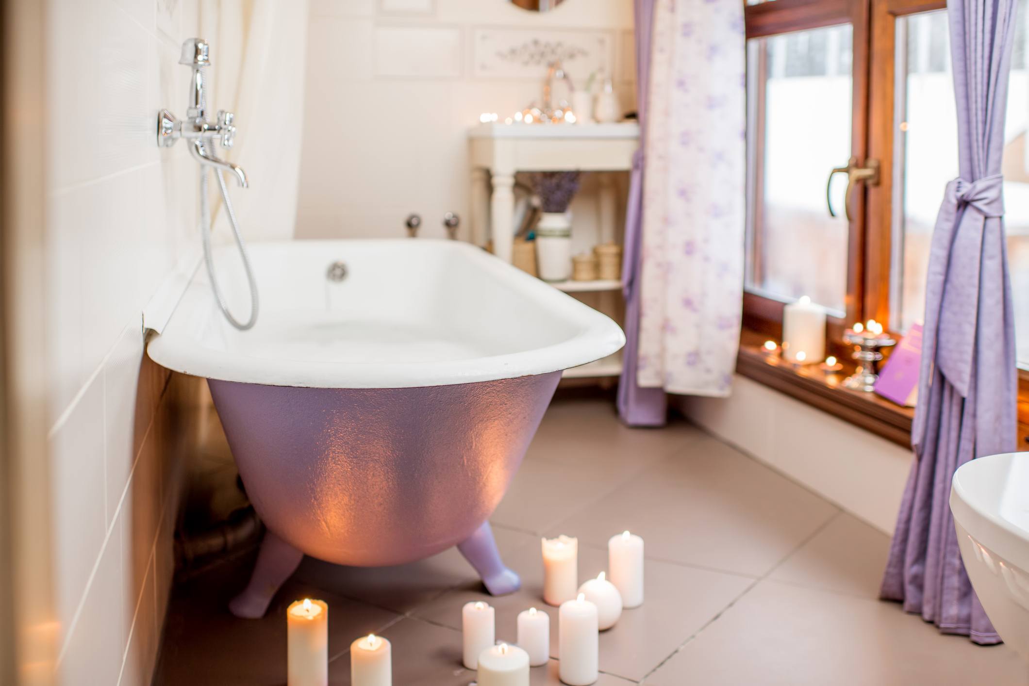 Bathroom interior with retro violet bath decorated with candles