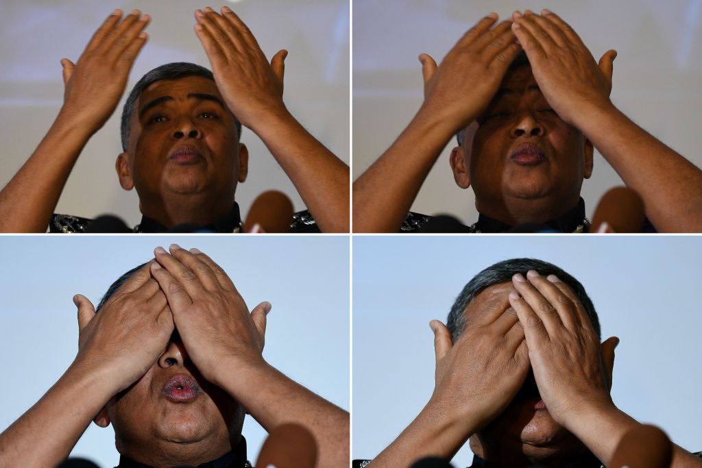 This combo of photographers taken on February 22, 2017 shows Royal Malaysian Police chief Khalid Abu Bakar demonstrating the actions of one of the women accused of being involved in the assassination of Kim Jong-Nam