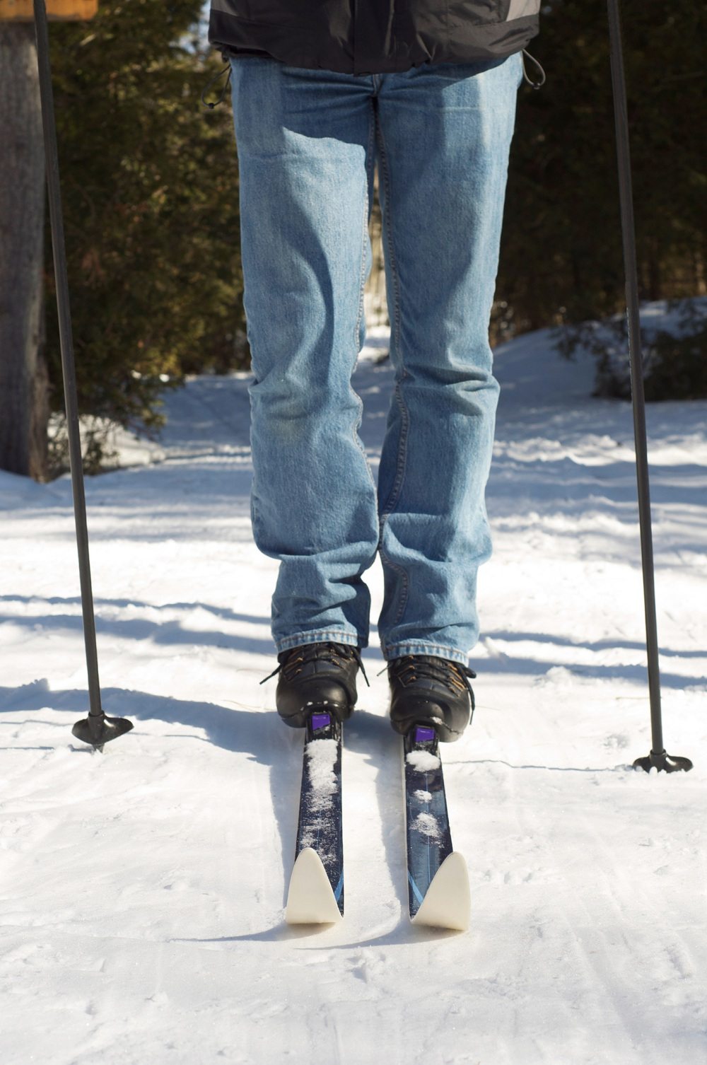 Man skiing in jeans A man stands with his cross country skis