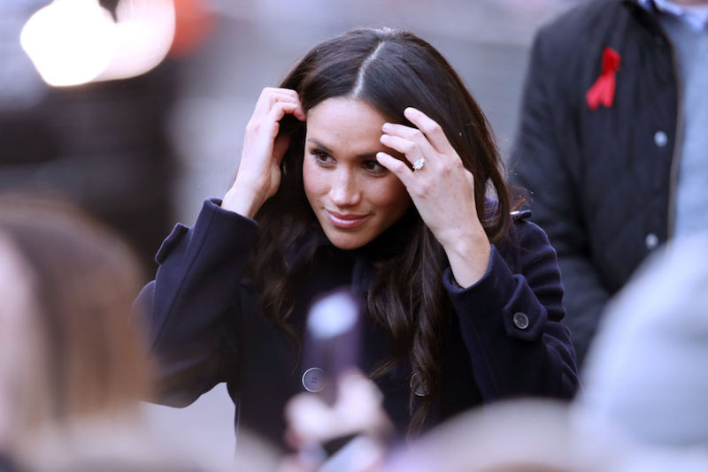 Meghan Markle pushes her hair back while walking towards the public.