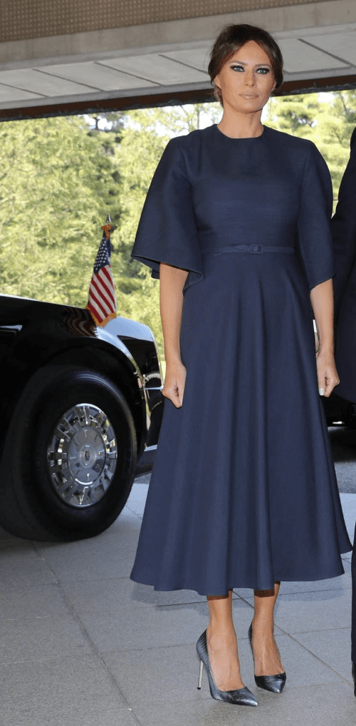 Melania Trump stands while wearing a navy dress and high heels. Melania Trump stands while wearing a navy dress and high heels.