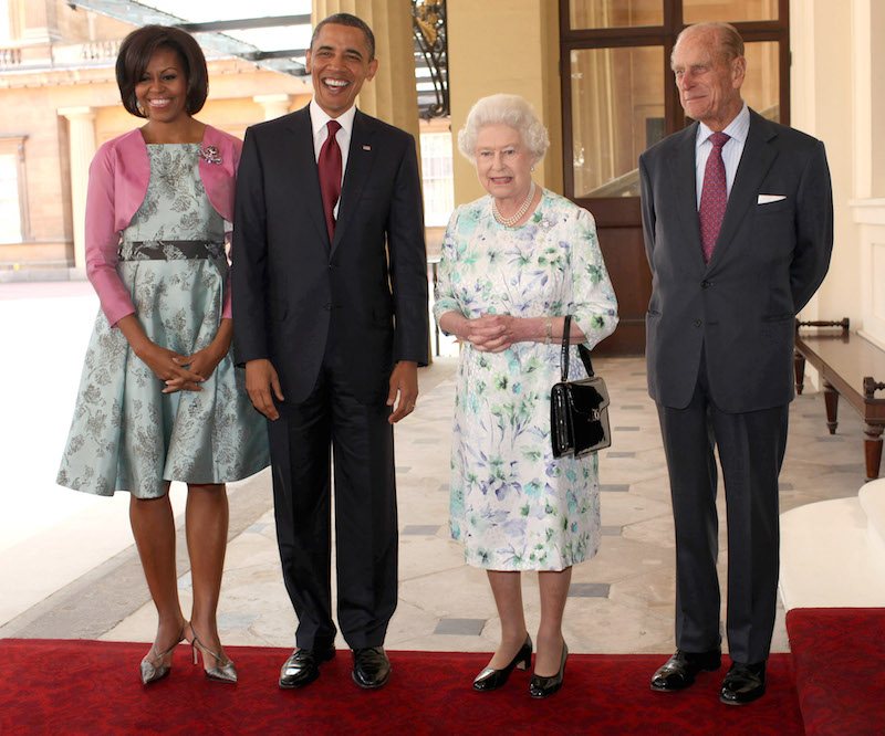 Barack Obama smiling with Michelle Obama as they stand next to Queen Elizabeth and Prince Phillip. 