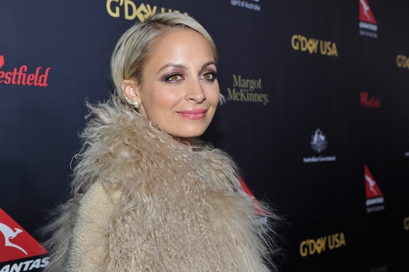 Nicole Richie smiles in a fur jacket on a red carpet.