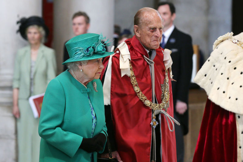 Queen Elizabeth stands next to Prince Charles as they attend a service at a cathedral. 