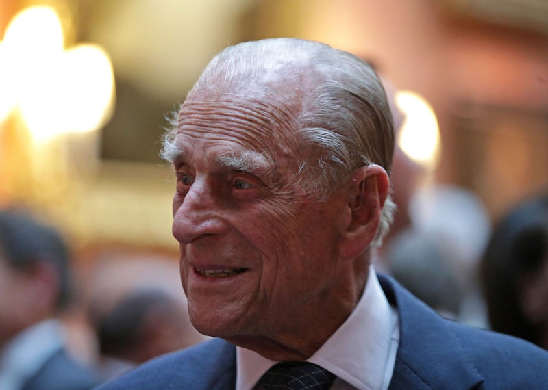Prince Phillip looking to the side and smiling while wearing a suit and tie.