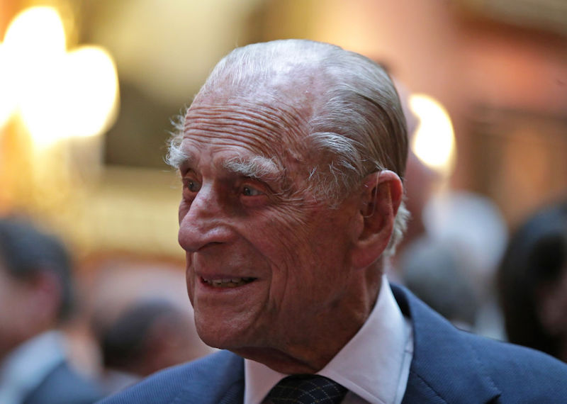 Prince Phillip looking to the side and smiling while wearing a suit and tie. Prince Phillip looking to the side and smiling while wearing a suit and tie.