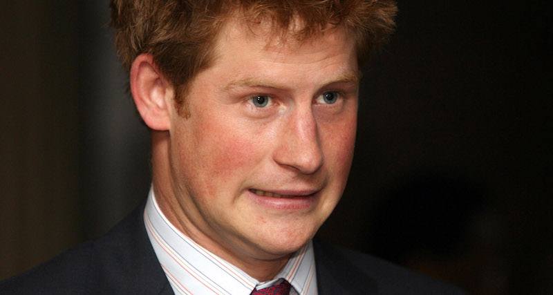 Prince Harry grimaces while wearing a black suit.