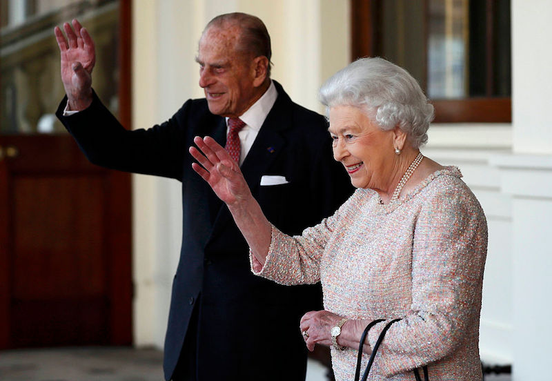 Prince Phillip waves while standing next to Queen Elizabeth. 
