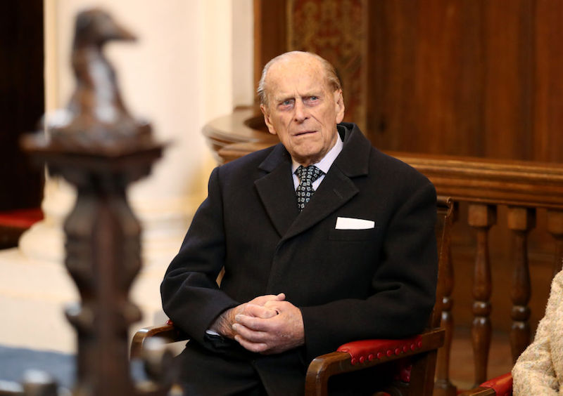 Prince Phillip sitting in a chair while wearing a black jacket and tie. Prince Phillip sitting in a chair while wearing a black jacket and tie.
