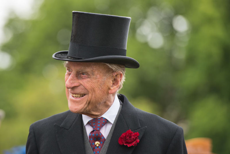 Prince Charles wearing a tall hat and a suit and tie. Prince Charles wearing a tall hat and a suit and tie.