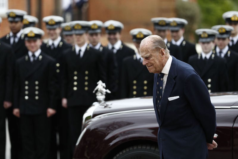 Prince Phillip stands in front of a naval army and shiny car. Prince Phillip stands in front of a naval army and shiny car.