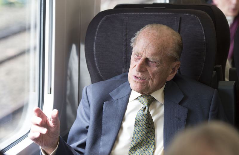 Prince Charles sits on a train. 