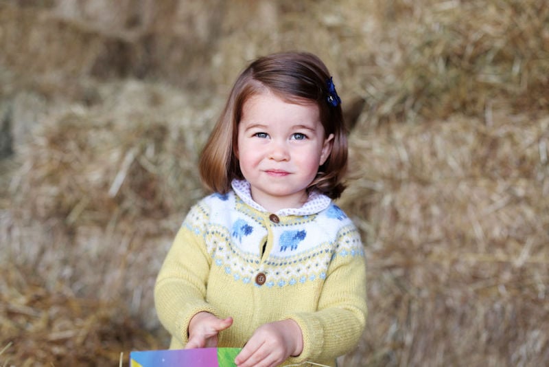 Princess Charlotte posing in a field while playing with a painting. 