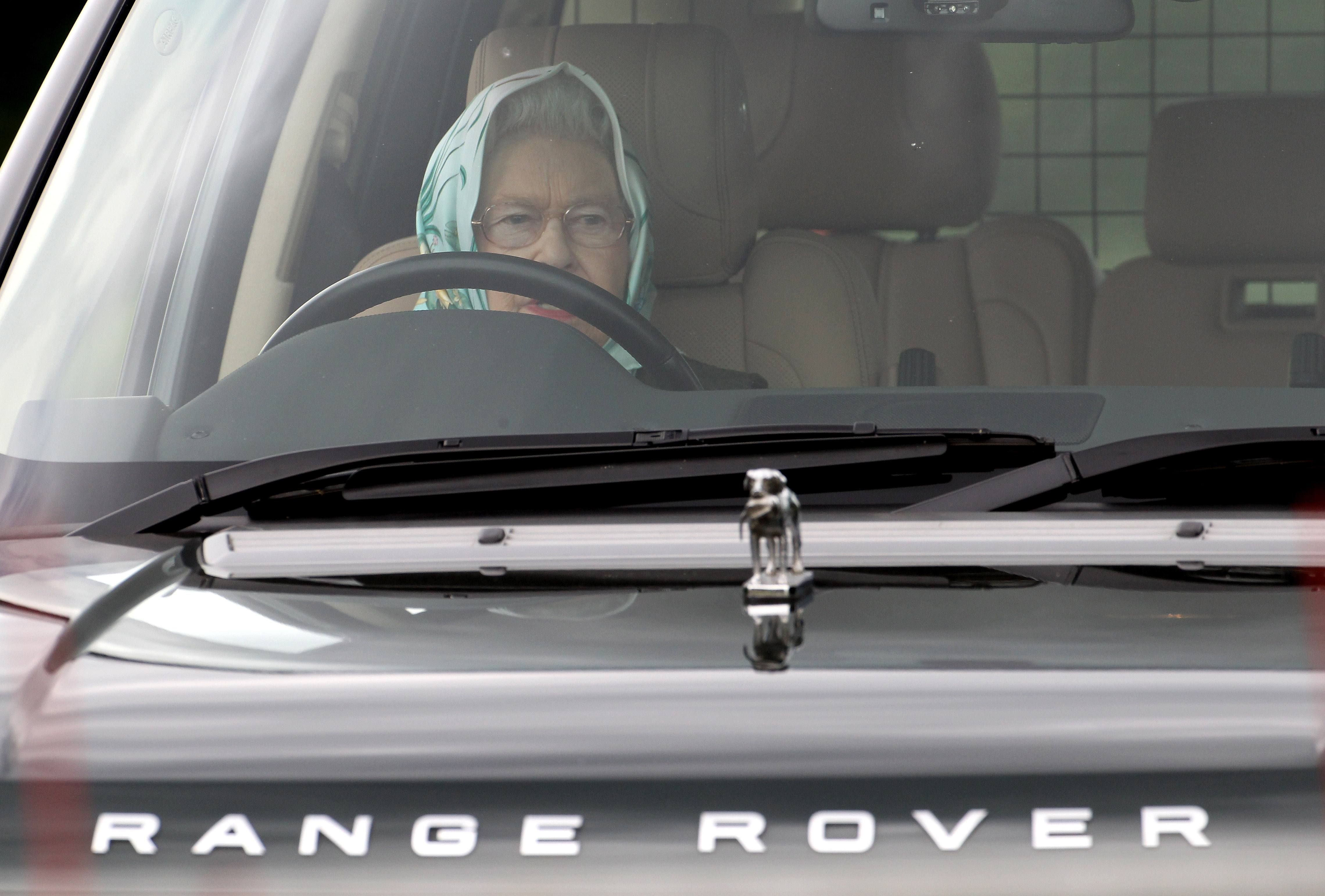 Queen Elizabeth drives a car with her hair in a scarf