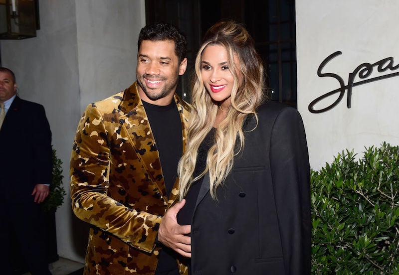 Russell Wilson places his hand on Ciara's baby bump as they smile and pose on a red carpet. Russell Wilson places his hand on Ciara's baby bump as they smile and pose on a red carpet.