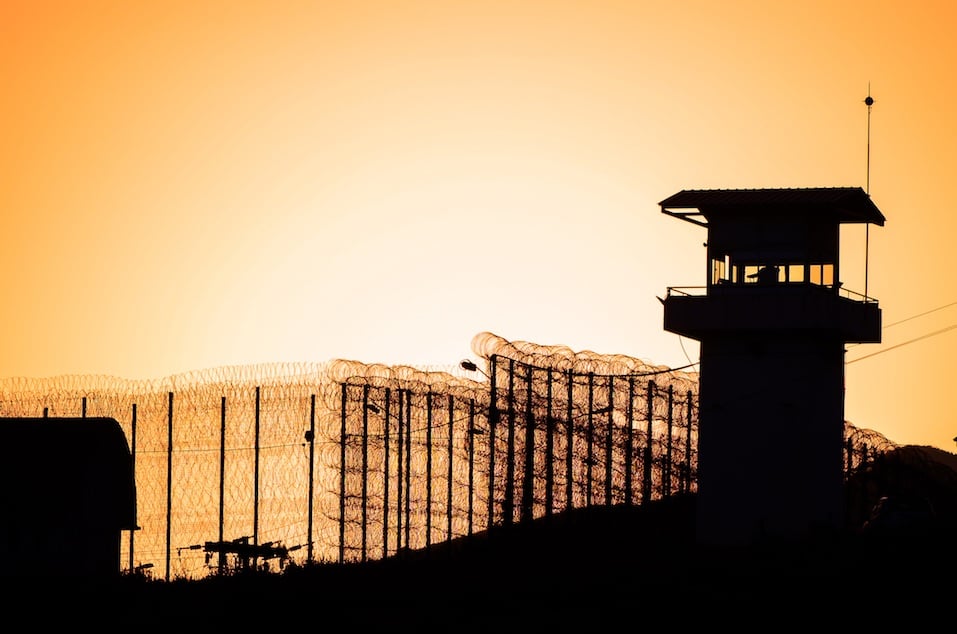 Silhouette of barbed wires and watchtower of prison.