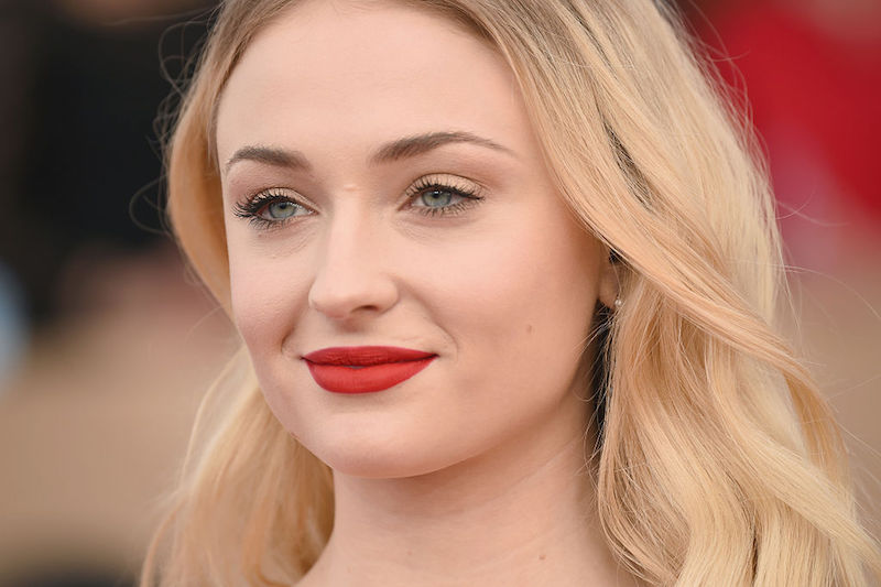 Sophie Turner smiling while wearing a bold red lipstick. Sophie Turner smiling while wearing a bold red lipstick.