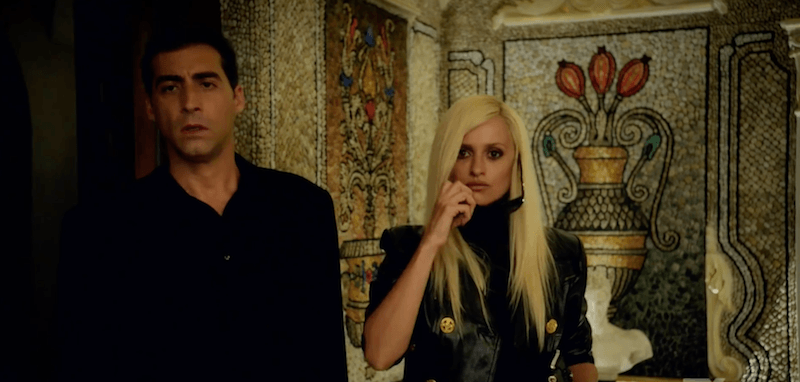 Donatella Versace standing with a man inside a decorated room. Donatella Versace standing with a man inside a decorated room.