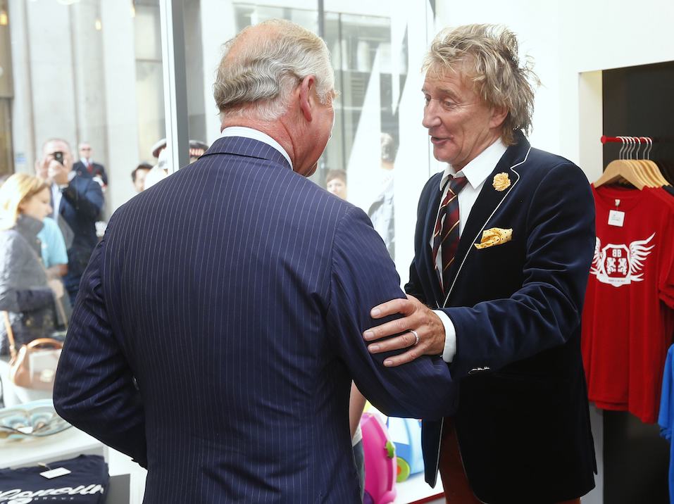 Rod Stewart (R) apologises to Prince Charles, Prince of Wales after arriving late for the opening of The Prince's trust 'Tomorrow's Shop'