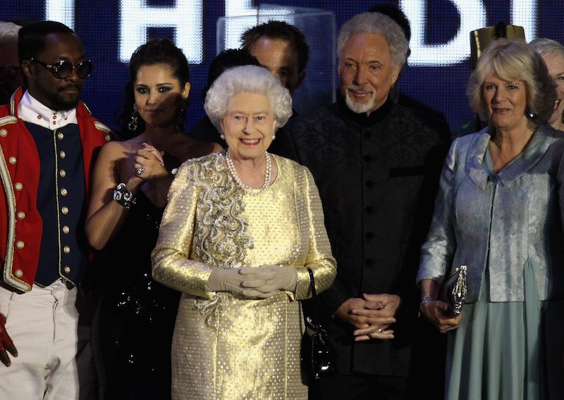 Queen Elizabeth stands and smiles with Tom Jones. Queen Elizabeth stands and smiles with Tom Jones.