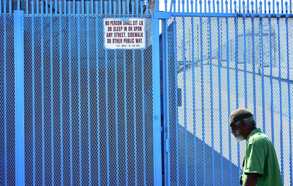 A man walks past a sign posting the ordinance which led to the explosion of tents housing the homeless on Los Angeles streets