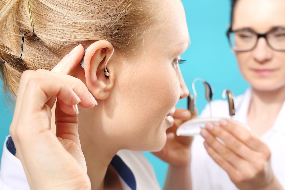 Woman puts on a hearing aid