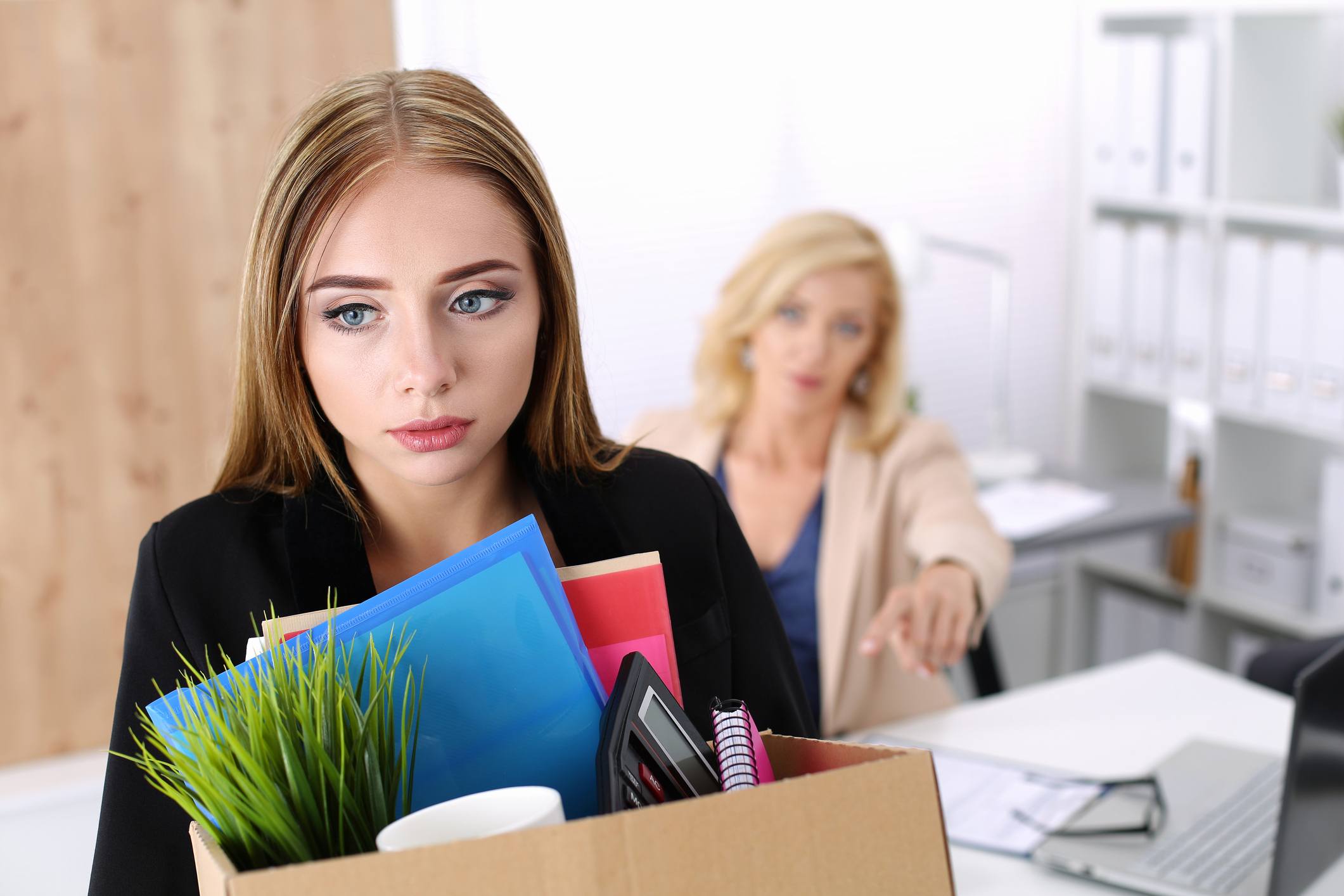Fired or laid off worker leaving the office with a box of her things