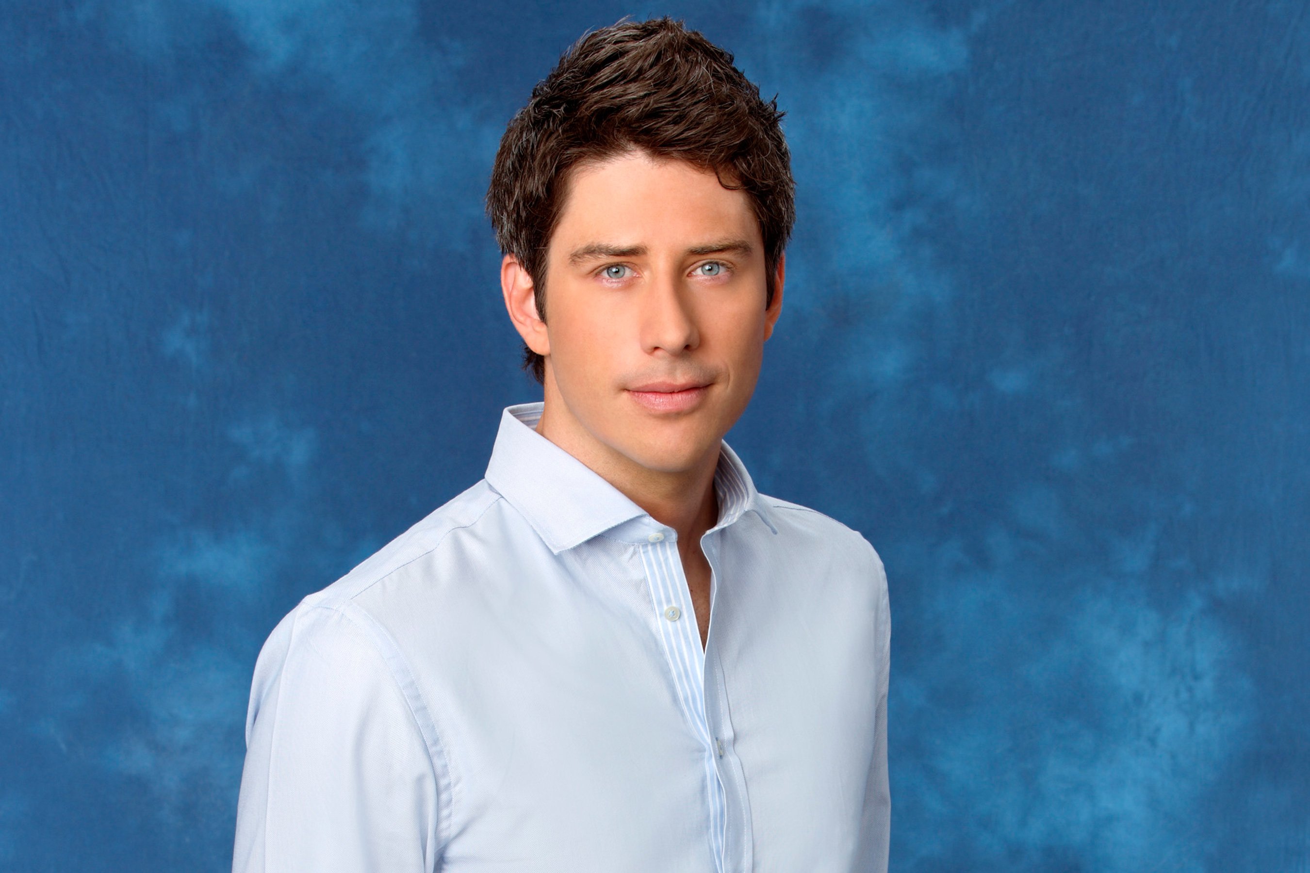 Arie Luyendyk Jr. poses in front of a blue background