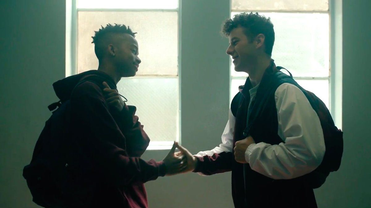 Two teenage boys looking at each other doing a handshake Two teenage boys looking at each other doing a handshake