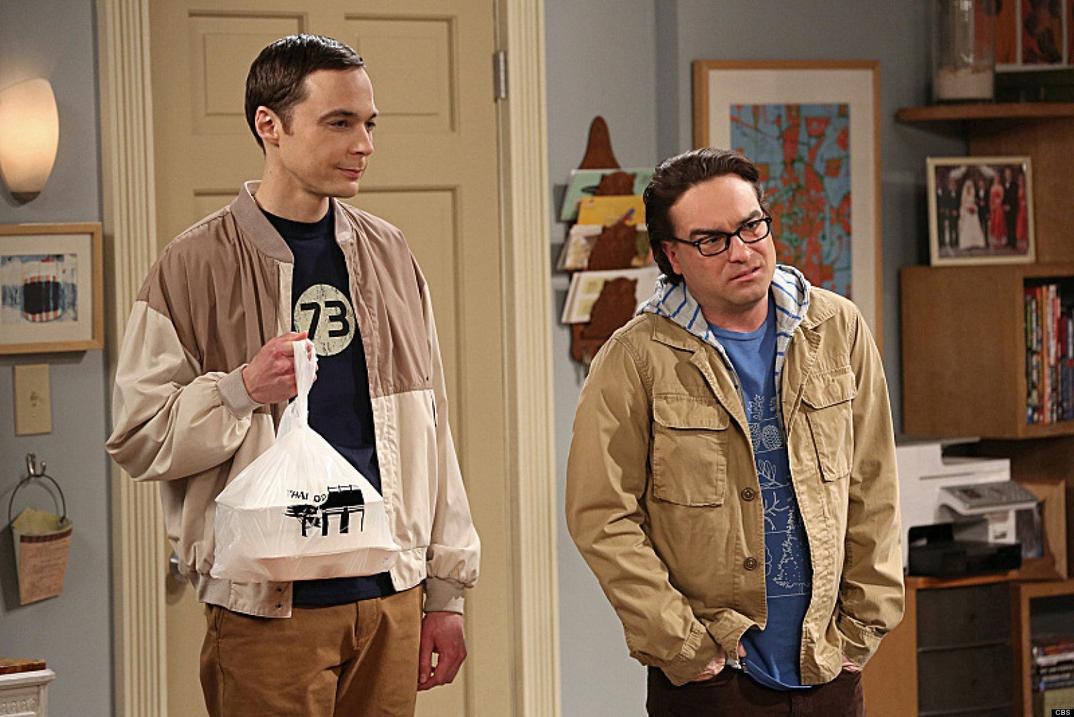 Sheldon and Leonard stand next to each other while holding bags of food