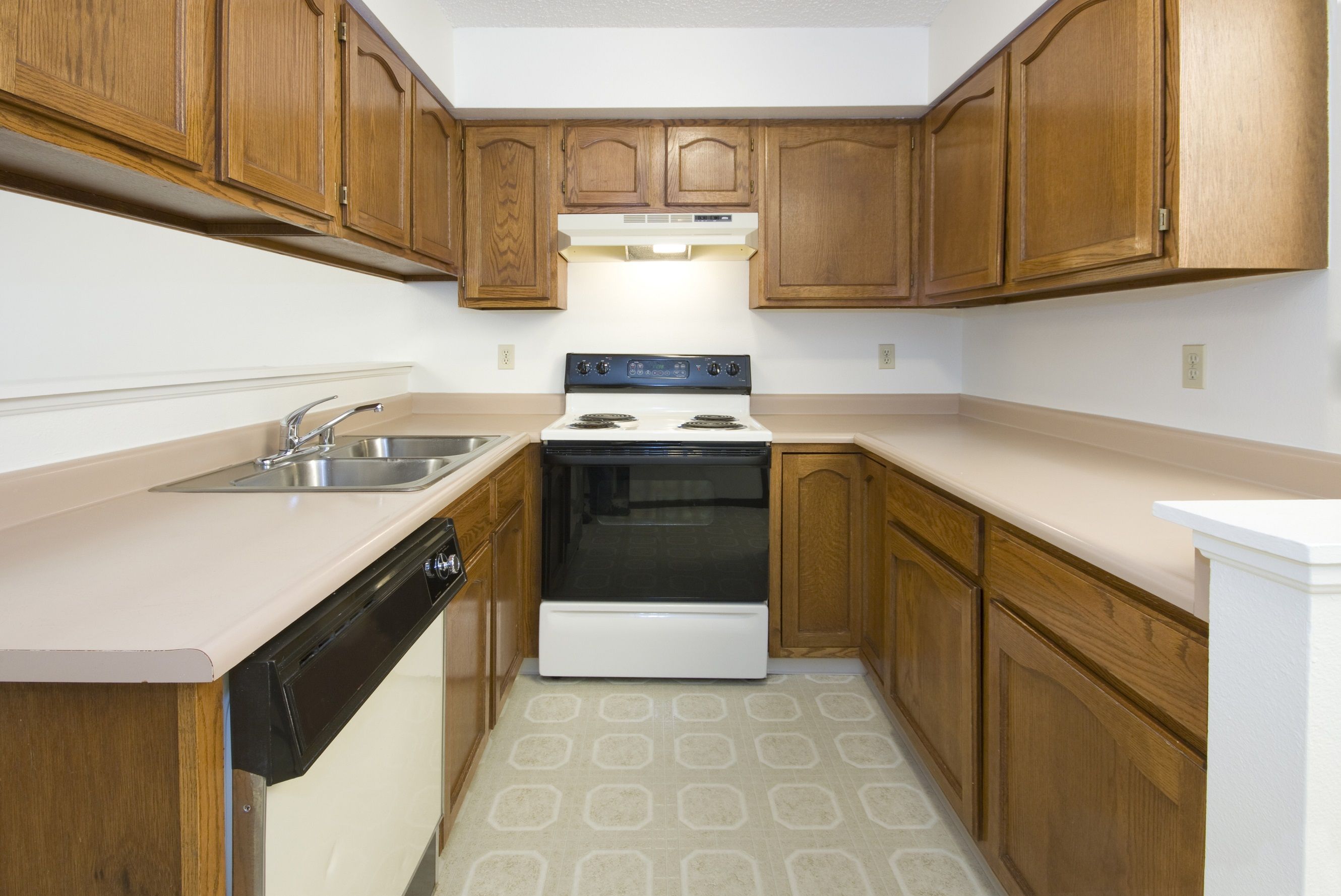 Old, dated kitchen with wood cabinets, laminate counters and old appliances