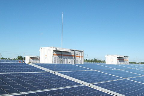 A SUNGROW solar system with a energy storage device in the background. A SUNGROW solar system with a energy storage device in the background.