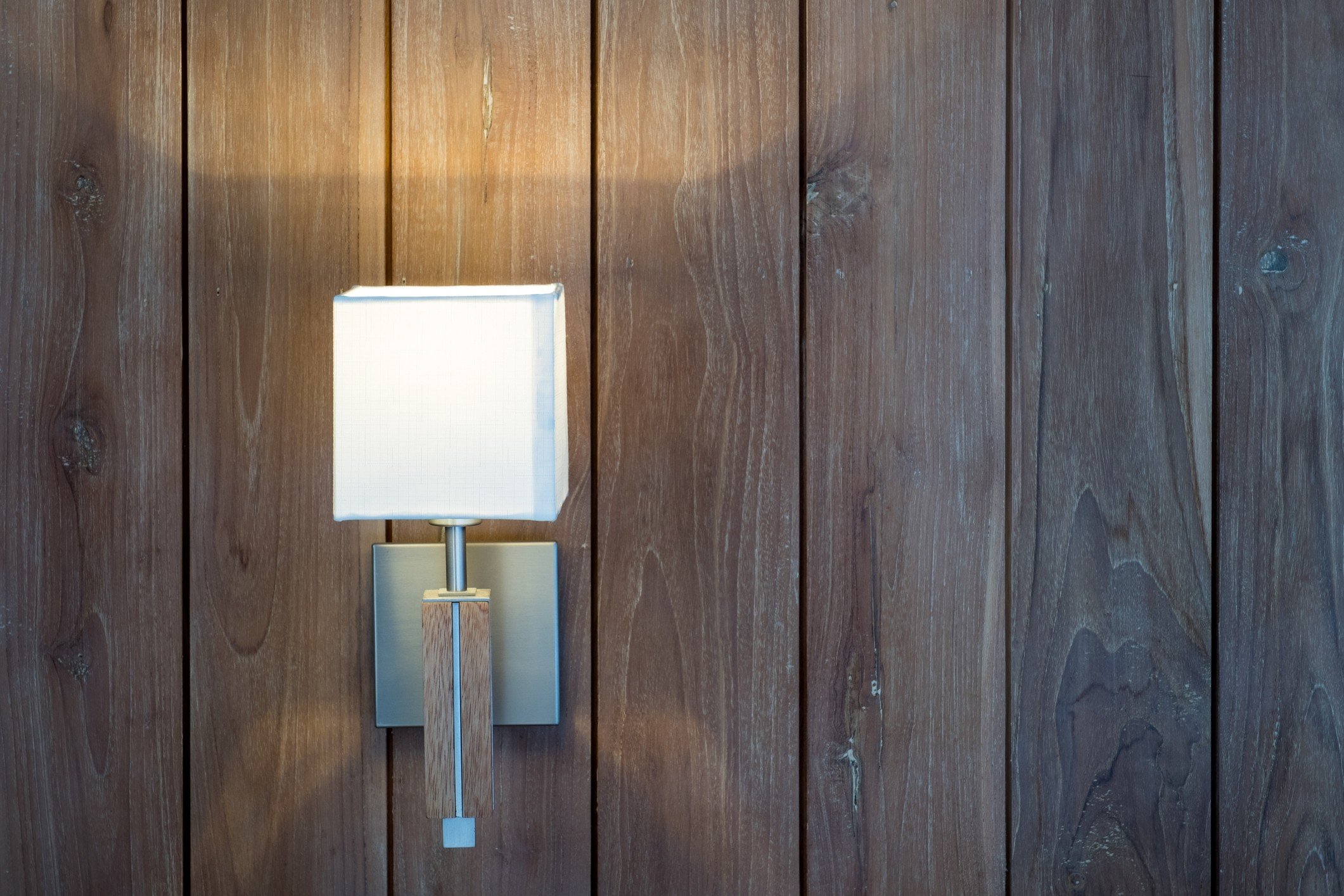 Square wall light on brown wood paneling