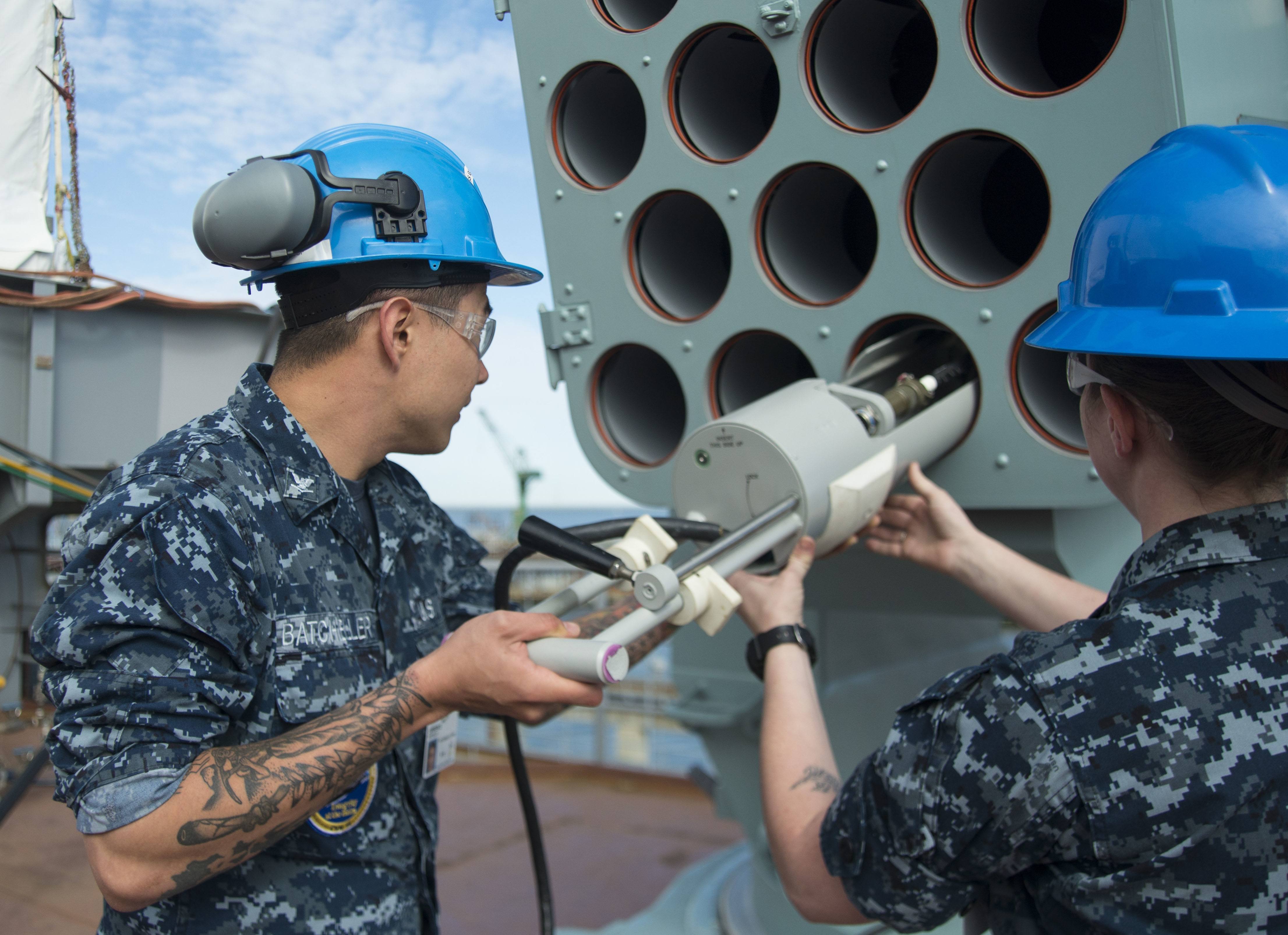 Fire Controlman 2nd Class Shelby Edson and Fire Controlman 3rd Class Lawrence Batcheller insert a Load-Out Test Adapter into a Rolling Airframe Missile (RAM) launching system Fire Controlman 2nd Class Shelby Edson and Fire Controlman 3rd Class Lawrence Batcheller insert a Load-Out Test Adapter into a Rolling Airframe Missile (RAM) launching system
