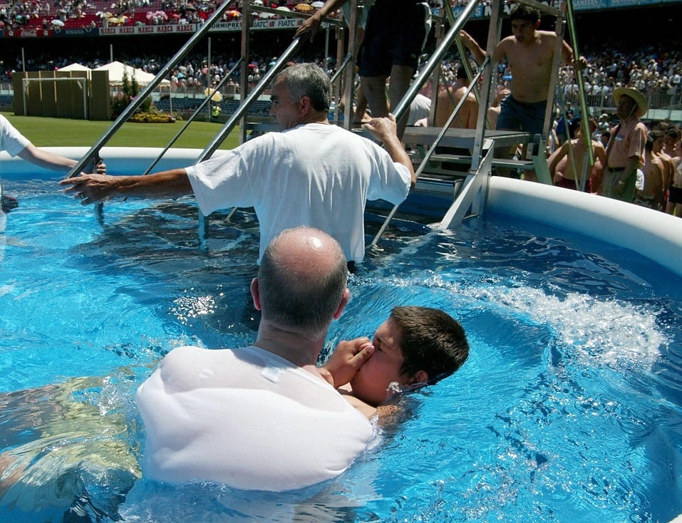 A boy is baptized in a pool during a Jehovah's Witnesses international assembly