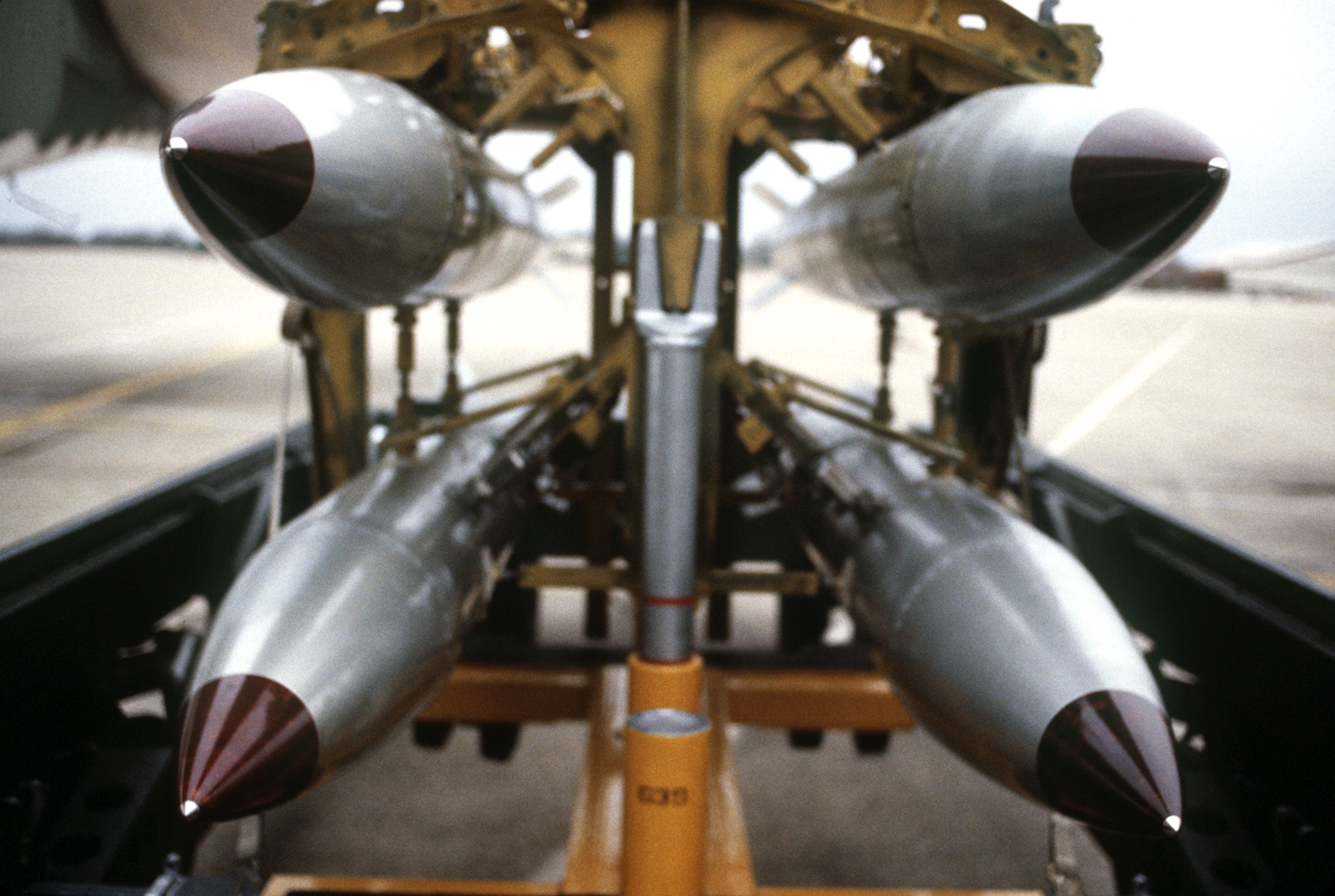 A front view of four nuclear free-fall bombs on a bomb cart.