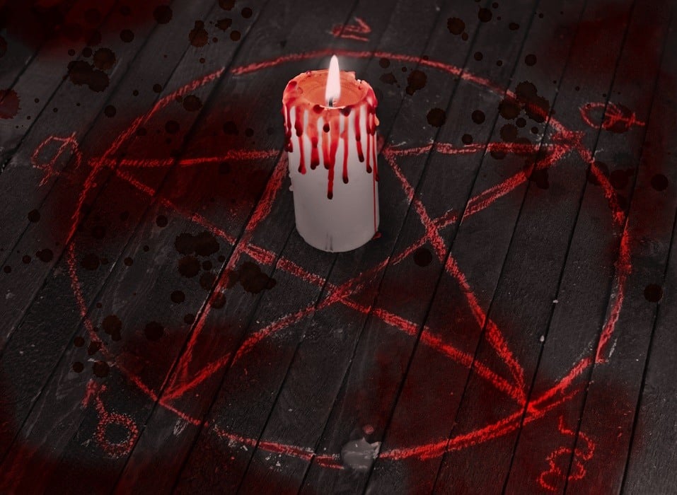 Bloody candle in pentagram circle Scary Halloween collage with black candle, blood drops and pentagram circle on wooden table