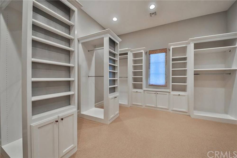 A large, white walk i closet with shelves and hanging space