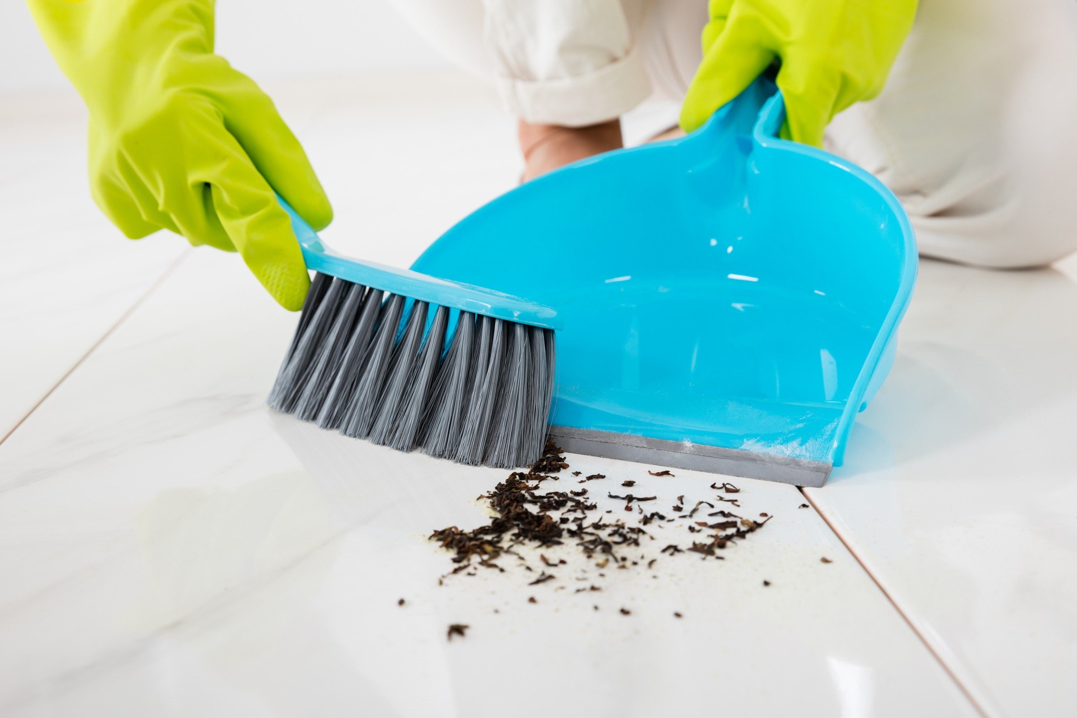 Person Sweeping Floor With Broom And Dustpan