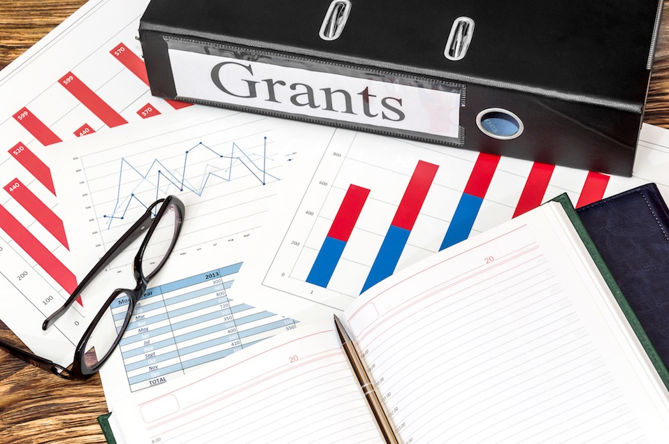 Folder labeled "Grants", glasses and notepad on graphs