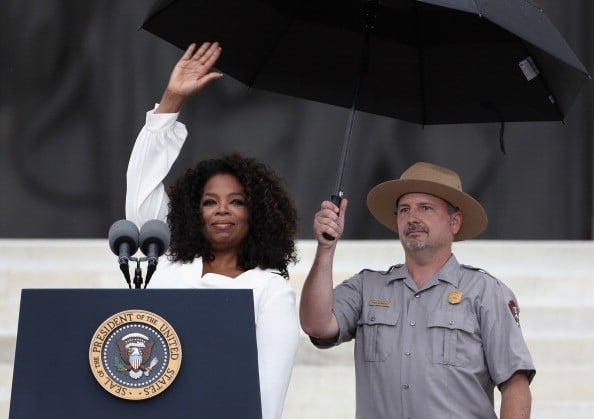 The former talk show host speaks during the Let Freedom Ring ceremony at the Lincoln Memorial in 2013 oprah at the lincoln memorial with a ranger holding an umbrella over her head