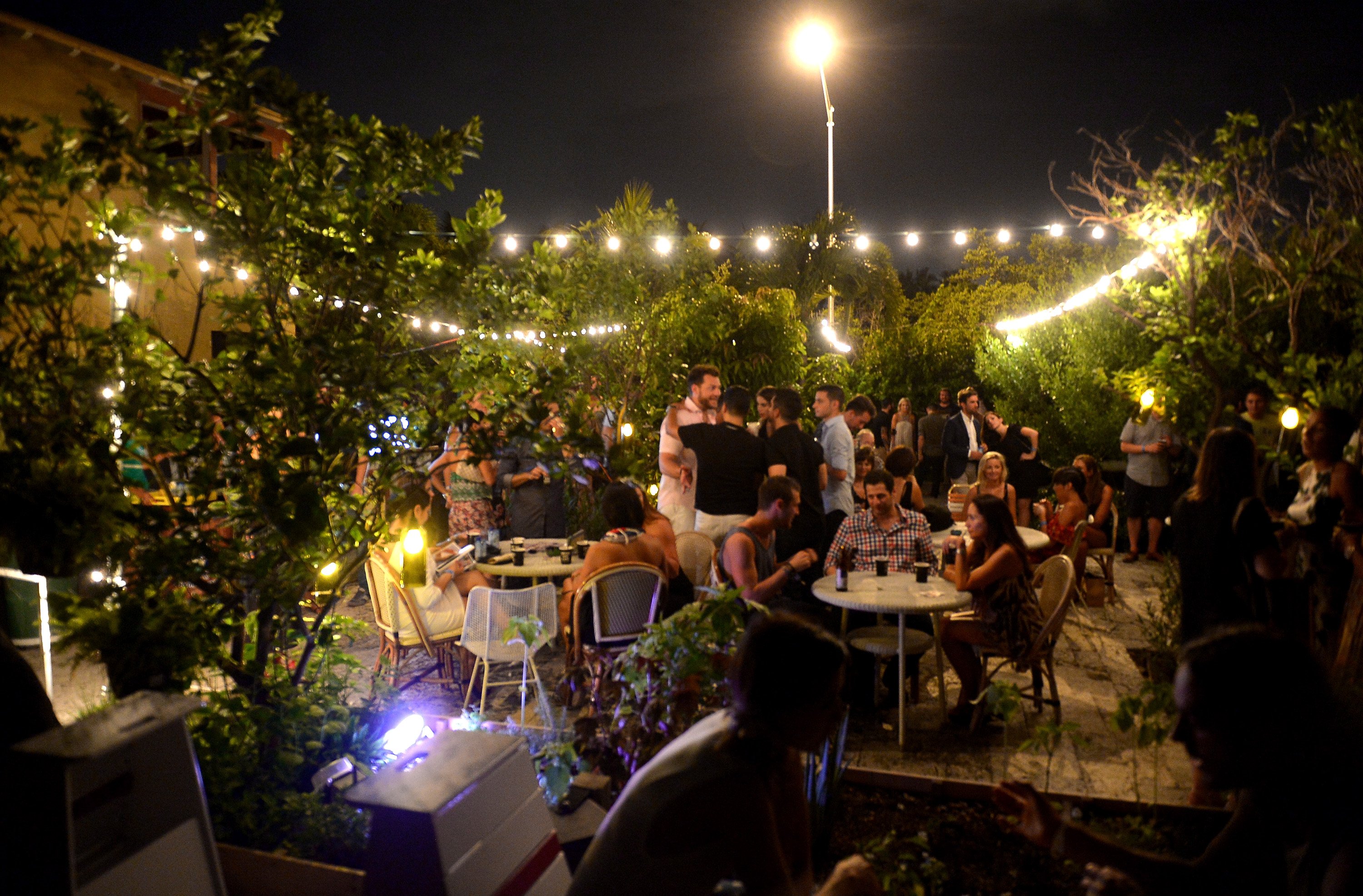 people at a rooftop party with string lights people at a rooftop party with string lights