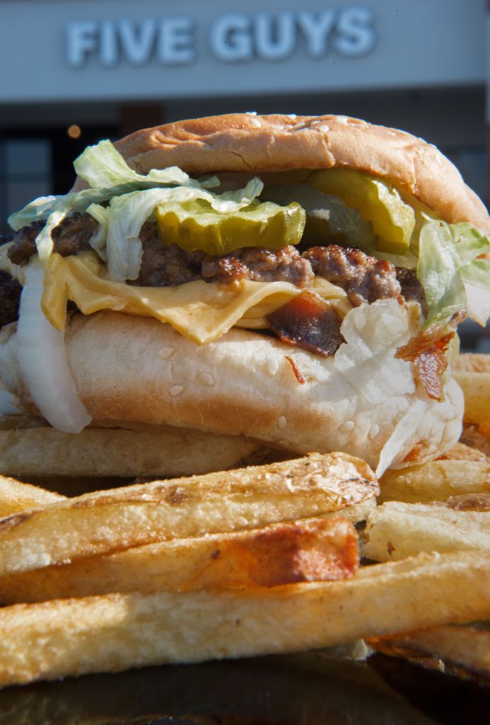 A bacon cheeseburger with French fries is viewed outside the popular Five Guys hamburger chain
