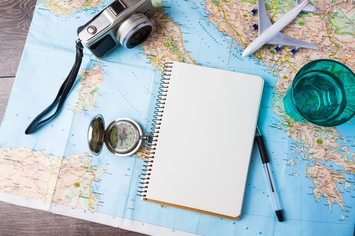 a camera and notebook spread over a map