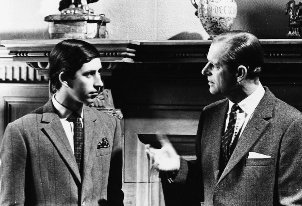Prince Charles And The Duke Of Edinburgh speaking in front of a fireplace. 